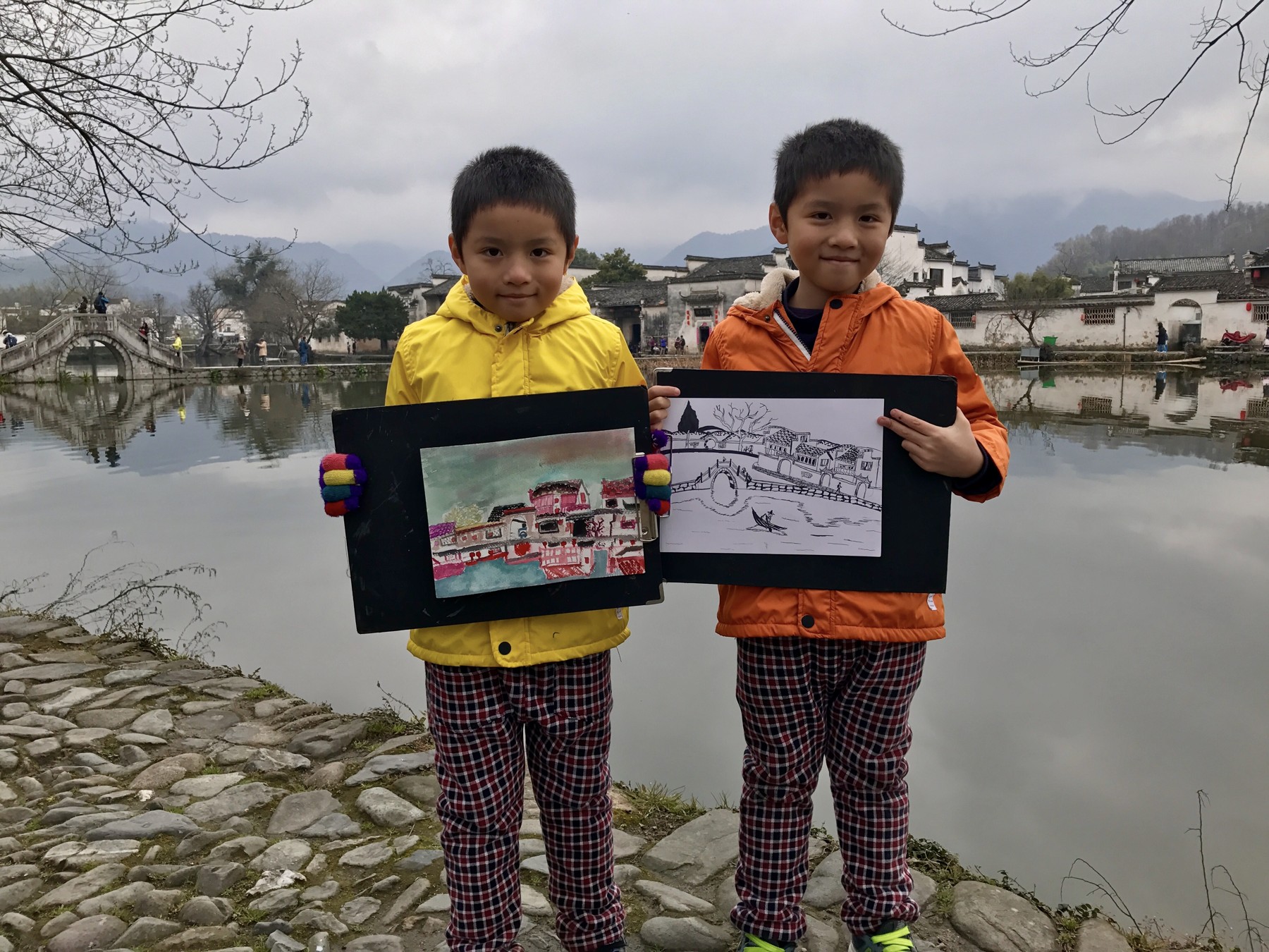My brother and me holding our drawings beside a lake as children
